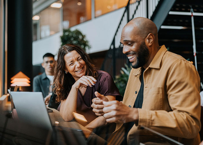 About us img- two people laughing looking at laptop screen